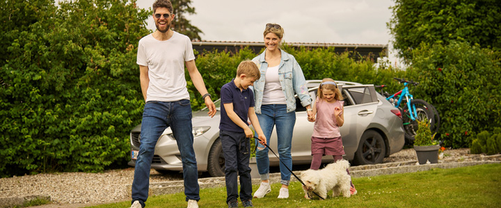 Junge Familie mit Hund starten in ihren Urlaub im Novasol Ferienhaus inmitten von grüner Natur.