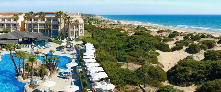 Die Luftaufnahme zeigt das TUI BLUE Playa La Barrosa direkt am langen Sandstrand der Costa de la Luz. Die Hotelanlage liegt eingebettet in die grüne Küstenlandschaft.